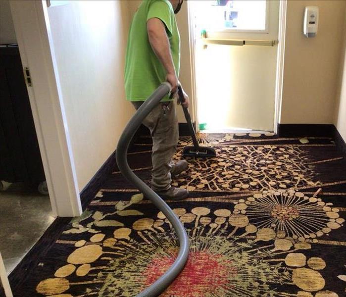 SERVPRO team members is extracting water from a hotel carpet.