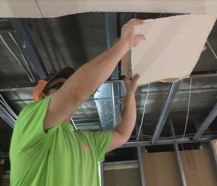 SERVPRO team member is removing parts of a ceiling.