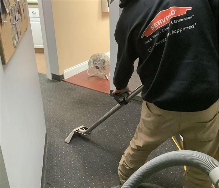 SERVPRO team member is extracting water from an office floor.