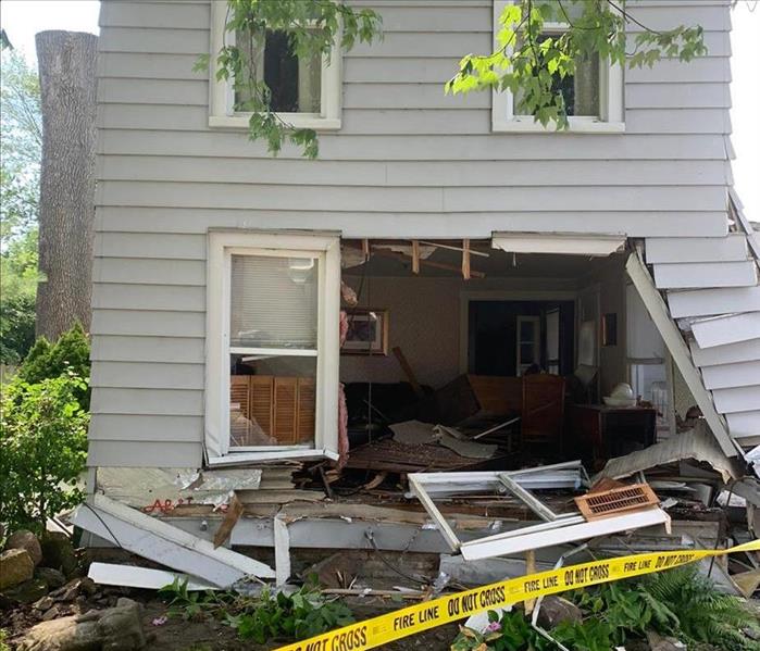 image of home severely damaged by thunderstorm causing a tree to fall