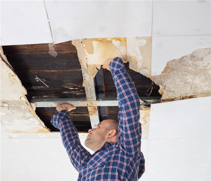 A partial fallen ceiling with a man fixing it.
